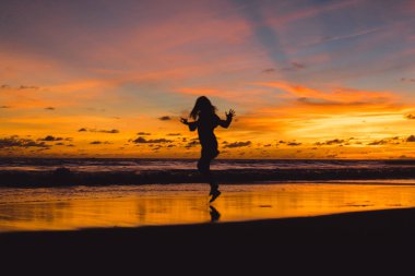 Kız batan güneşin fonunda atlıyor.