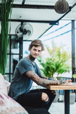 bir sipariş için bekleyen bir smartphone, içecekler kahve, dövmeli bir adam bir kafede kullanır.