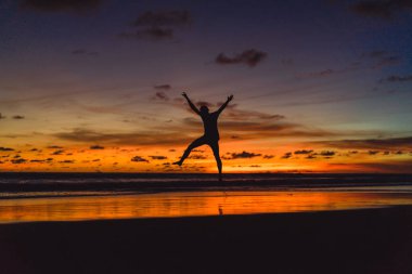 gün batımında okyanusun kıyısında kişi. adam batan güneşin fonunda atlar.