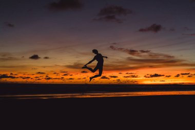 gün batımında okyanusun kıyısında kişi. adam batan güneşin fonunda atlar.