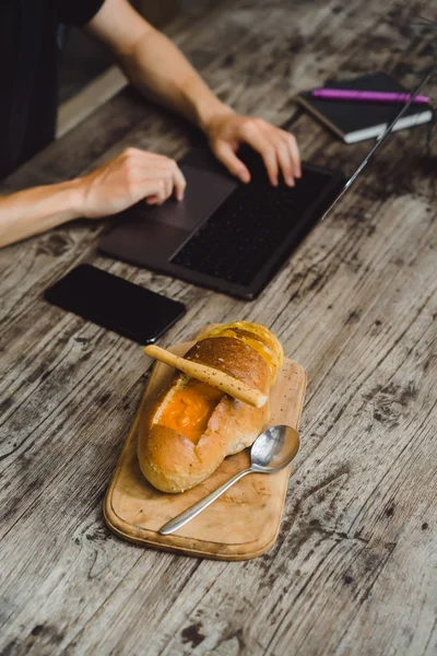 man in a cafe working in a laptop, eating, working, smartphone