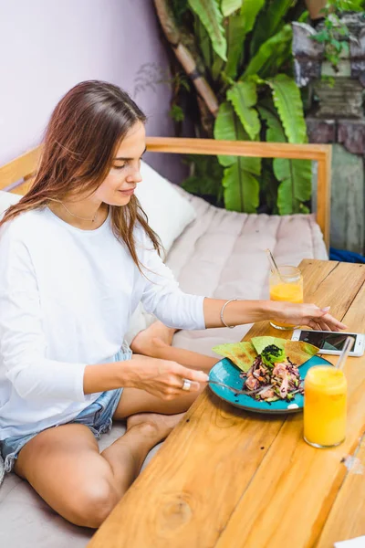 美しい女性にはおしゃれなカフェで 健康的な朝食 フルーツ 絞りたてのジュース 朝食熱帯の場所 — ストック写真