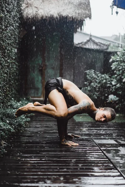 young tattooed man posing in the rain