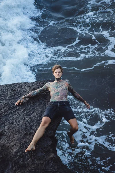 Hombre Tatuado Borde Acantilado Salpicaduras Olas Oceánicas —  Fotos de Stock