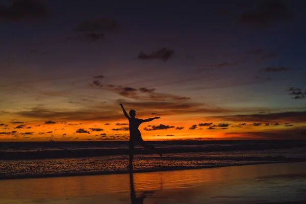 person on the shore of the ocean at sunset. man jumps against the backdrop of the setting sun.