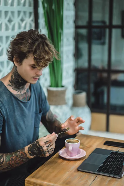tattooed hands of man. drinking coffee and using laptop concept
