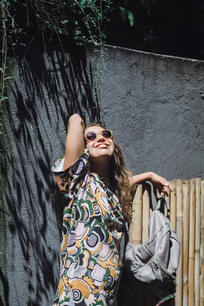 bir sırt çantası, güneş gözlüğü, tropikal bahçede giyen kızla