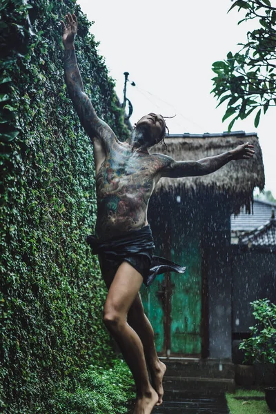 年轻的纹身男子在雨中摆姿势 — 图库照片