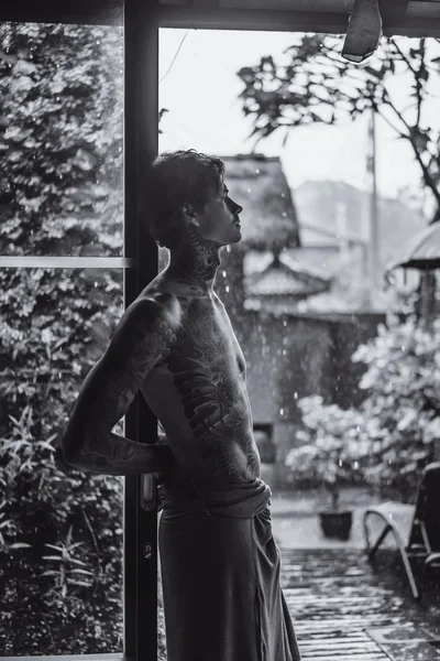 Genç dövmeli adam karşı yağmur poz