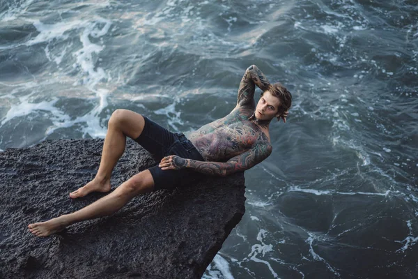 Tetovaný Muž Okraji Útesu Tryskající Mořských Vln — Stock fotografie