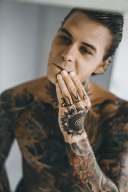 bir ayna, onun elinde bir tıraş jilet önünde genç bir yakışıklı dövmeli adam sabah tıraş.