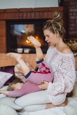 genç kadın bir çocukla. Anne ve oğlu, şömine yakın eğleniyor kandırıyorsunuz demektir.