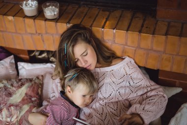 Genç anne ve oğlu şömine yakın bir masal kitabı mı okuyorsun.