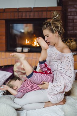 genç kadın bir çocukla. Anne ve oğlu, şömine yakın eğleniyor kandırıyorsunuz demektir.