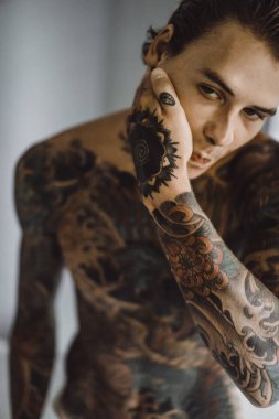 bir ayna, onun elinde bir tıraş jilet önünde genç bir yakışıklı dövmeli adam sabah tıraş.