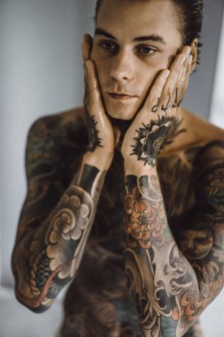 bir ayna, onun elinde bir tıraş jilet önünde genç bir yakışıklı dövmeli adam sabah tıraş.