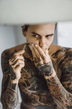 bir ayna, onun elinde bir tıraş jilet önünde genç bir yakışıklı dövmeli adam sabah tıraş.