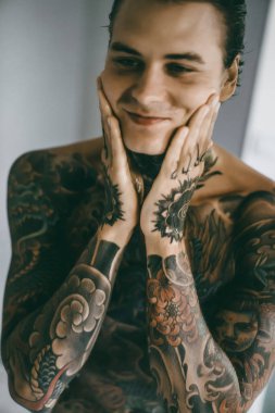 bir ayna, onun elinde bir tıraş jilet önünde genç bir yakışıklı dövmeli adam sabah tıraş.