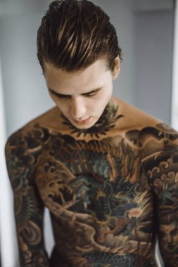 bir ayna, onun elinde bir tıraş jilet önünde genç bir yakışıklı dövmeli adam sabah tıraş.