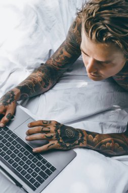 Yatakta dizüstü bilgisayarda çalışan, postaları kontrol eden, film izleyen, müzik dinleyen, Skype 'ta konuşan bir adam..