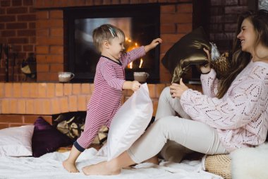 genç kadın bir çocukla. Anne ve oğlu, şömine yakın eğleniyor kandırıyorsunuz demektir.