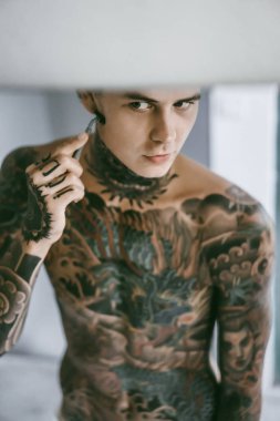 bir ayna, onun elinde bir tıraş jilet önünde genç bir yakışıklı dövmeli adam sabah tıraş.