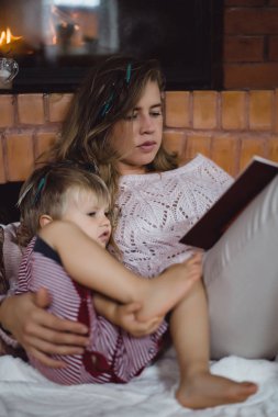 Genç anne ve oğlu şömine yakın bir masal kitabı mı okuyorsun.