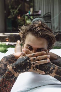 yakışıklı, Genç bir dövmeli adam sabah yatakta yastık fırlatır. Bahçe yatağında