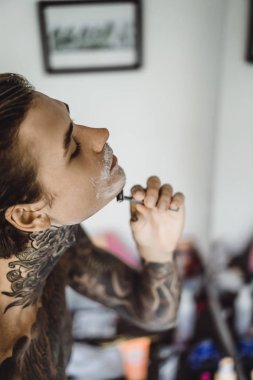 bir ayna, onun elinde bir tıraş jilet önünde genç bir yakışıklı dövmeli adam sabah tıraş.