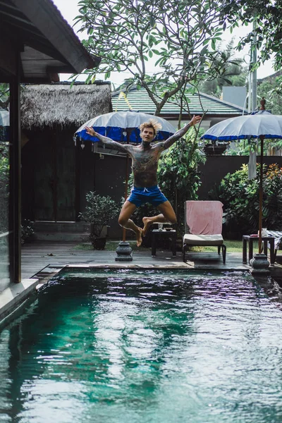 young handsome man in tattoos resting in the outdoor pool. A tattooed man in the pool is having fun. on bali, indonesia