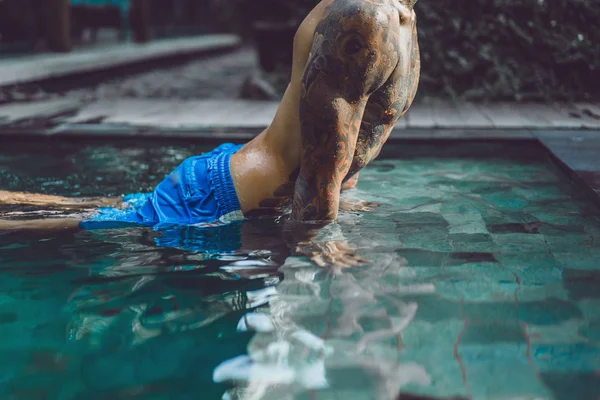 屋外プールで休憩の入れ墨で若いハンサムな男 プールで刺青男が楽しんでいます バリ島 インドネシアの — ストック写真