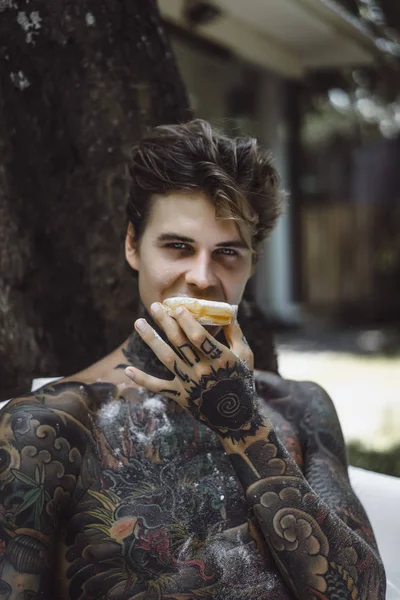 Jonge Knappe Getatoeëerde Man Ontbijten Bed Buitenlucht Tuin Donuts Koffie — Stockfoto