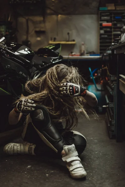 ガレージに長い髪の美しい女の子がバイクを修理します — ストック写真