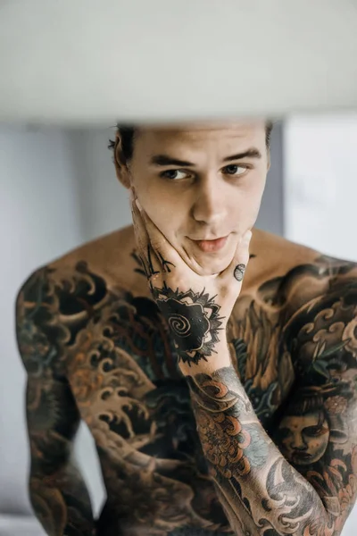 bir ayna, onun elinde bir tıraş jilet önünde genç bir yakışıklı dövmeli adam sabah tıraş.