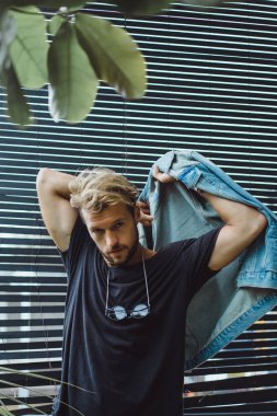 tropikal bir yerde, palmiye ağaçları ve yeşil, güneş gözlüklü bir arka plan üzerinde poz genç çekici adam