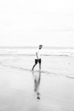 okyanus plaj boyunca kumlu bir plaj üzerinde yürüyen genç çekici adam