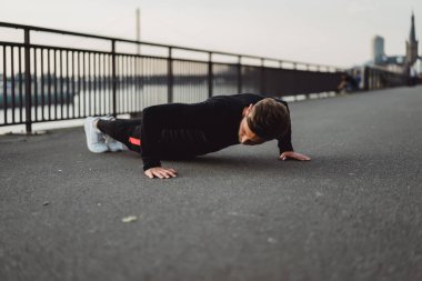 Yakışıklı atletik genç adam dışarıda egzersiz yapıyor.