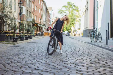 Şehirde bisiklet süren genç bir kadın.