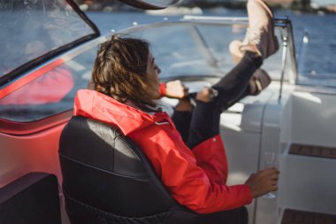 Kırmızı pelerinli güzel bir kadın yatta şampanya içiyor..