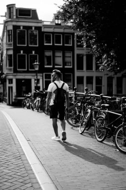 Bir insan bir sırt çantası ile Amsterdam sokaklarında yürüyor.