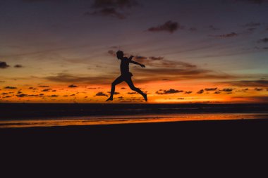 insanlar gün batımında okyanus kıyısında. adam batan güneşin fonunda atlar.