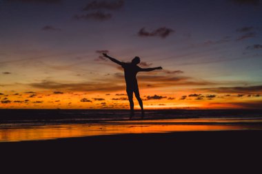 insanlar gün batımında okyanus kıyısında. adam batan güneşin fonunda atlar.