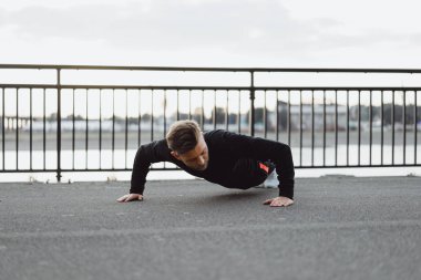 Yakışıklı atletik genç adam dışarıda egzersiz yapıyor.