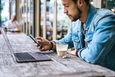 genç çekici iş adamı için bir dizüstü bilgisayar, bir kafe eserlerinde kahve içiyor.