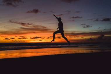 insanlar gün batımında okyanus kıyısında. adam batan güneşin fonunda atlar.