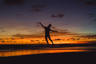 insanlar gün batımında okyanus kıyısında. adam batan güneşin fonunda atlar.