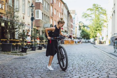 Şehirde bisiklet süren genç bir kadın.