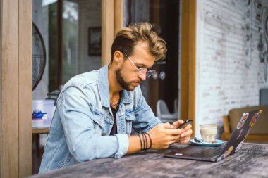genç çekici iş adamı için bir dizüstü bilgisayar, bir kafe eserlerinde kahve içiyor.