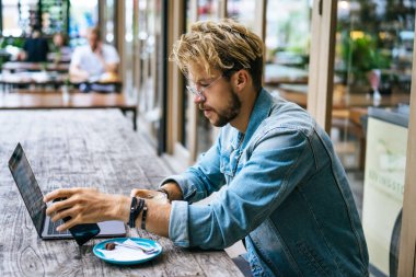 genç çekici iş adamı için bir dizüstü bilgisayar, bir kafe eserlerinde kahve içiyor.
