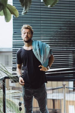 tropikal bir yerde, palmiye ağaçları ve yeşil, güneş gözlüklü bir arka plan üzerinde poz genç çekici adam